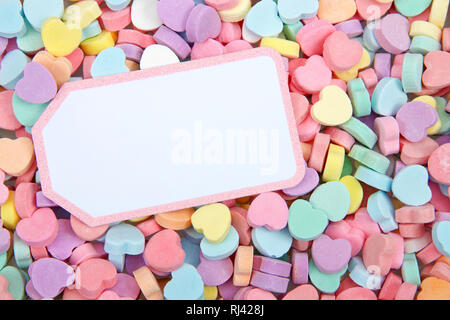 pastel colored candy hearts on yellow background with copy space