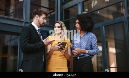 Small group of business people discussing work. Three business professionals talking over new business plan. Stock Photo