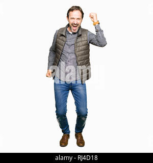 Middle age handsome man wearing winter vest Dancing happy and cheerful, smiling moving casual and confident listening to music Stock Photo
