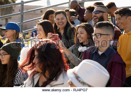 Happy Latinx fans taking selfie in bleachers at baseball game