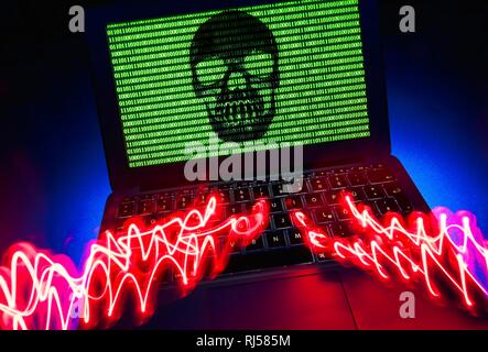Laptop with skull and crossbones and binary numbers on screen, symbol image malware, virus alarm, computer crime Stock Photo