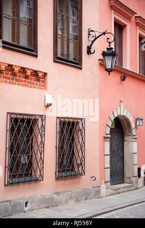 Grating window old fancy lantern sag on pink painted wall in Old Town alley, Tenement houses building with decorative gateway in Warsaw, Poland, Stock Photo