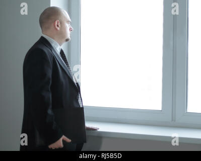 serious confident businessman looks out the window of the office Stock Photo