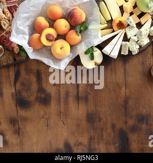 Appetizers table for wine with border. Various wine snacks: grapes, peach, apricot, pear, apples, jamon, hard cheese, brie cheese and roquefort cheese Stock Photo