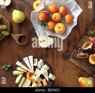 Appetizers table for wine. Various wine snacks: grapes, peach, apricot, pear, apples, jamon, hard cheese, brie cheese and roquefort cheese on wooden t Stock Photo