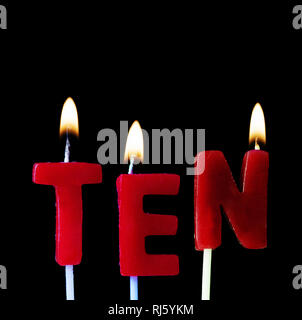 Ten spellt out in red birthday candles against a black background Stock Photo