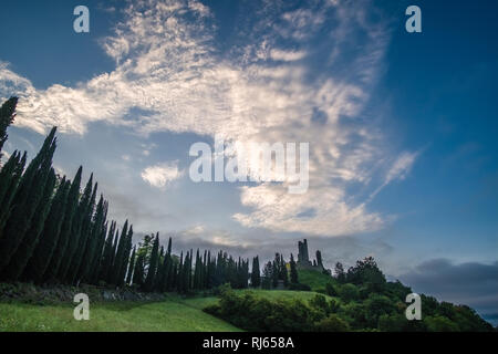 Typical hilly Tuscan countryside with fields and cypresses, Castello di Romena located on top of a hill, at sunrise Stock Photo