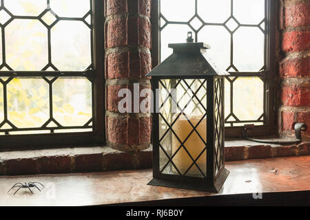 Alte Laterne mit einer Kerze steht vor einem mittelalterlichen Fenster, Stock Photo