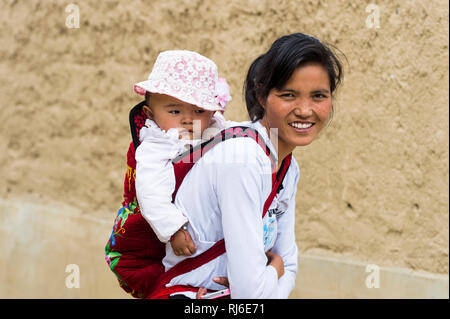 Tibet, Shigatse, Altstadt, Frau trägt Baby auf dem Rücken Stock Photo