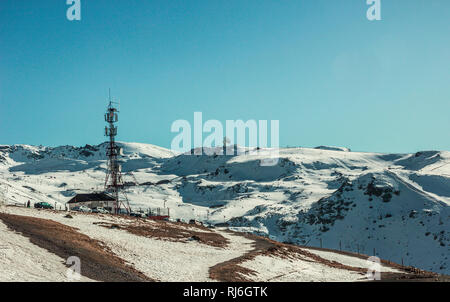 Tv, Radio and parabolic antenna in Sierra Nevada in front of snowy mountains with blue sky in background Stock Photo