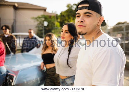 Portrait confident Latinx young man with friends in parking lot