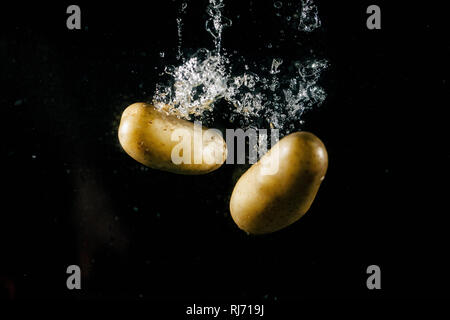 Two large potatos fall in water and make bubbles Stock Photo