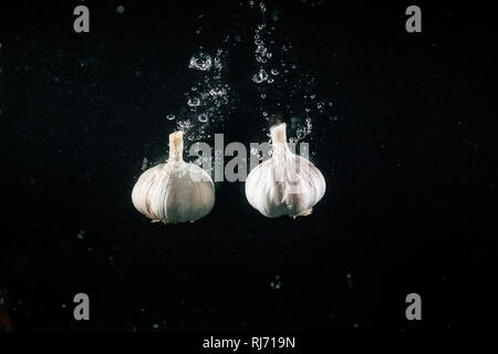 Two pieces of garlic make bubbles falling in water Stock Photo