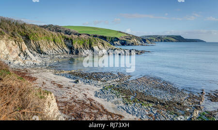 A beautiful sunny clear early morning on the Cornish coastal path at Polridmouth near Menabilly looking towards Lankelly Cliffs, Fowey and Polruan. Stock Photo