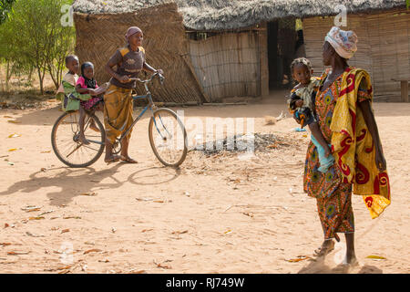 Karfiguela village, Banfora, Cascades Region, Burkina Faso, 6th December 2016; Sanata Kone, benificiary, (red and grey outfit), talking with friends on the way to her field. Stock Photo