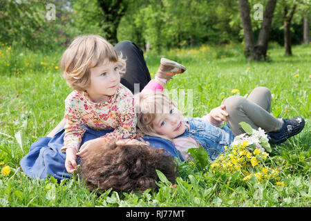 2 Mädchen, 5 und 3 Jahre alt, spielen mit der Mutter auf einer Frühlingwiese Stock Photo