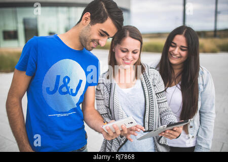 Drei Jugendliche mit Tablet und Smartphone unterwegs