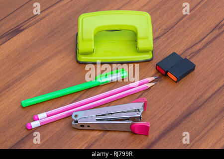 Colored pen pencils and rubbers, school and office supplies on brown wood table background. Stock Photo