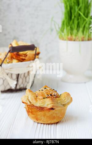 Meat pies from puff pastry with sesame seeds on a light background. Fresh Traditional Australian meat mini pie. Stock Photo