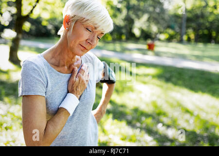 Senior woman with chest pain suffering from heart attack during jogging Stock Photo