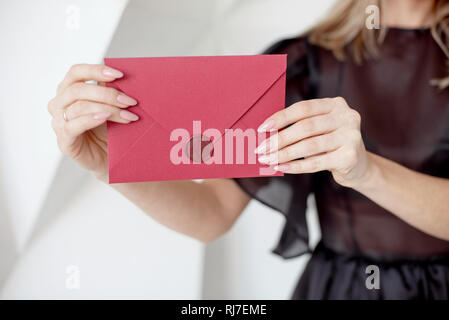 Close-up woman with slim body holding invitation envelope card in hands, rear veaw. Stock Photo