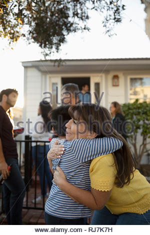Latinx grandmother and grandson hugging in front yard
