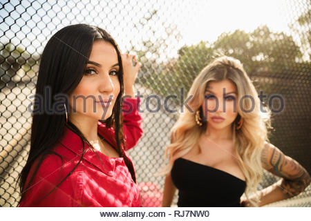 Portrait confident, tough Latinx young women friends at fence