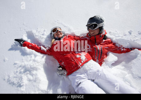 Paar im Schnee liegend im Skigebiet Ehrwalder Alm, Wettersteingebirge, Tirol, Österreich Stock Photo