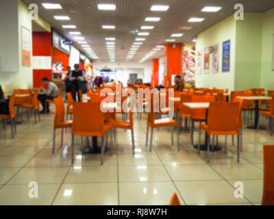 Empty yellow color chairs arranged in the row with the blurred people background in the hall. dining room with orange chairs, blurred. Stock Photo
