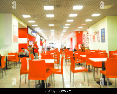 Empty yellow color chairs arranged in the row with the blurred people background in the hall. dining room with orange chairs, blurred. Stock Photo