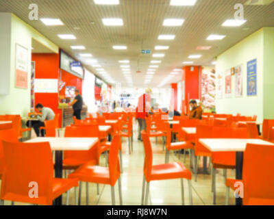 Empty yellow color chairs arranged in the row with the blurred people background in the hall. dining room with orange chairs, blurred. Stock Photo