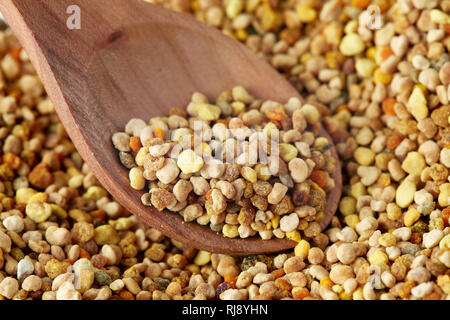 Close up of bee pollen grains in wooden spoon Stock Photo