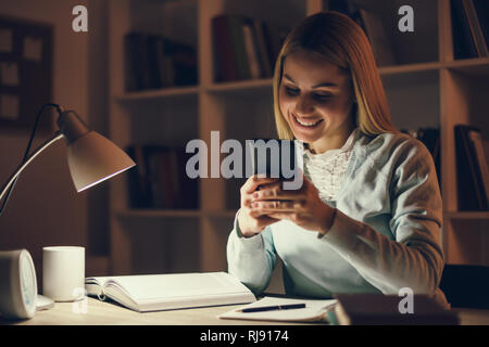 Student learning at home. Using smartphone. Stock Photo