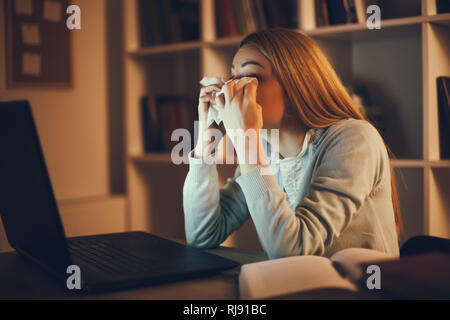 Tired student learning at home. She is rubbing her eyes. Stock Photo