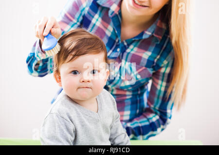 Mother brushing hair of her baby boy Stock Photo