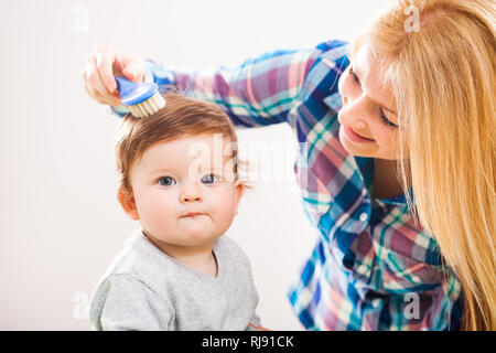 Mother brushing hair of her baby boy Stock Photo