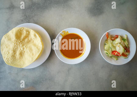 Malaysian street food a delicious Indian recipe for Beriayani and Roti Canai called popodum, curry and acar on table setup. Stock Photo