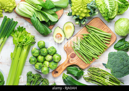 Vegan concept. Various ingredients, green vegetables on white table broccoli sprouts peas avocado courgette beans bok choy celery, top view Stock Photo