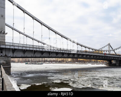 view of Krymsky (Crimean) Bridge over frozen Moskva River in Moscow city in overcast winter day. Krymsky Bridge is the only suspension bridge in all o Stock Photo