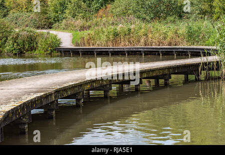 Winding foot bridge though the park leading onto stone path. Tranquil Stock Photo