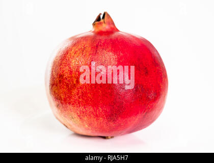 whole ripe red pomegranate fruit on plate on white background Stock Photo