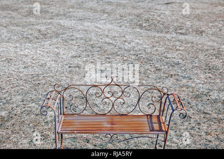 filigree rusty park bench in front of meadow area Stock Photo