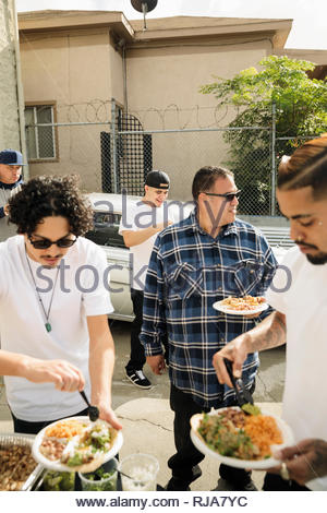 Latinx men friends enjoying taco lunch in driveway