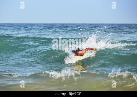 Young man surfing in sea against clear blue sky. Tangalle, Sri Lanka. Stock Photo