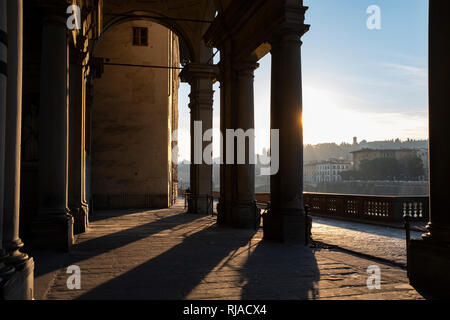 Early morning sunlight casting long shadows through the columns of the entrance to the Uffizi Gallery on the banks of the River Arno Florence Italy Stock Photo