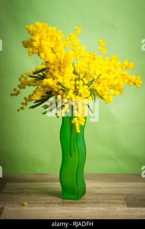 Spring bouquet of mimosa in a green vase Stock Photo