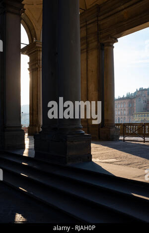 Early morning sunlight casting long shadows through the columns of the entrance to the Uffizi Gallery on the banks of the River Arno Florence Italy Stock Photo