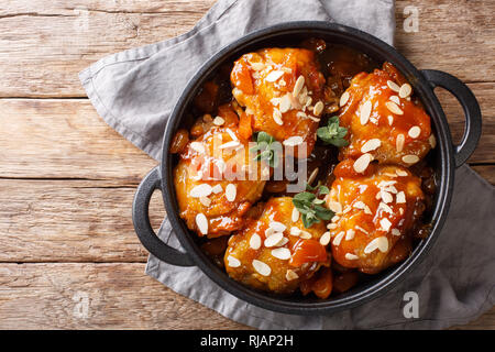 Fried glazed chicken thighs with dried apricots and almonds closeup in a pan on the table. horizontal top view from above Stock Photo