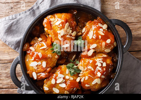 Roasted chicken thighs in apricot glaze with almonds close-up in a frying pan. Horizontal top view from above Stock Photo