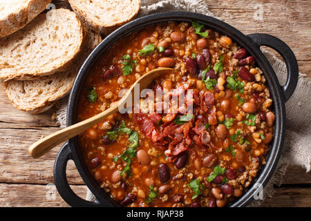 Crock pot beans with ground beef, bacon in a spicy sauce closeup in a bowl on the table. horizontal top view from above Stock Photo